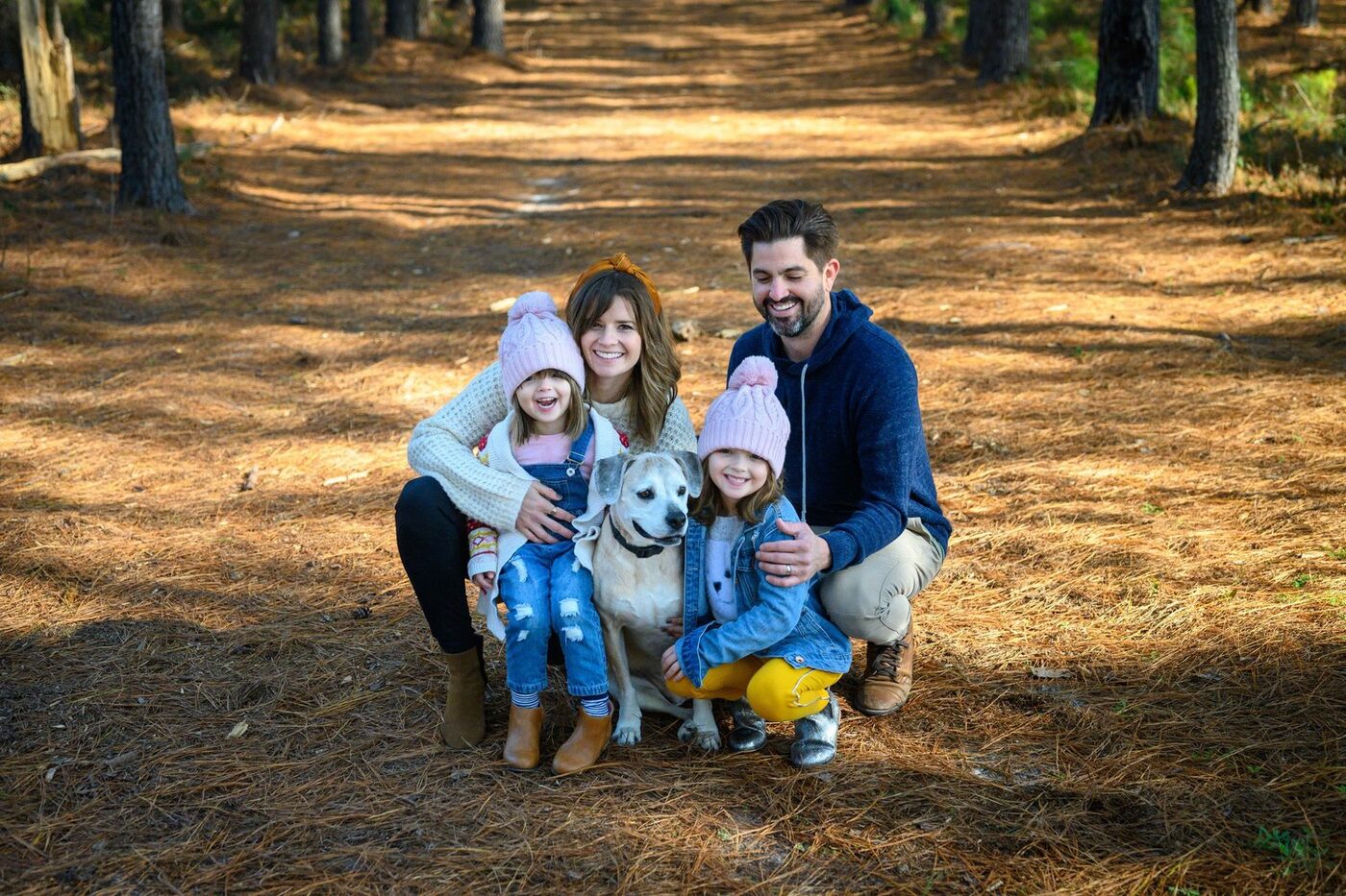 Bryan and Jessie Judge with their daughters and their dog among the pines
